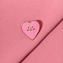 Load image into Gallery viewer, Heart-shaped pin with a cartoon character on a pink fabric background
